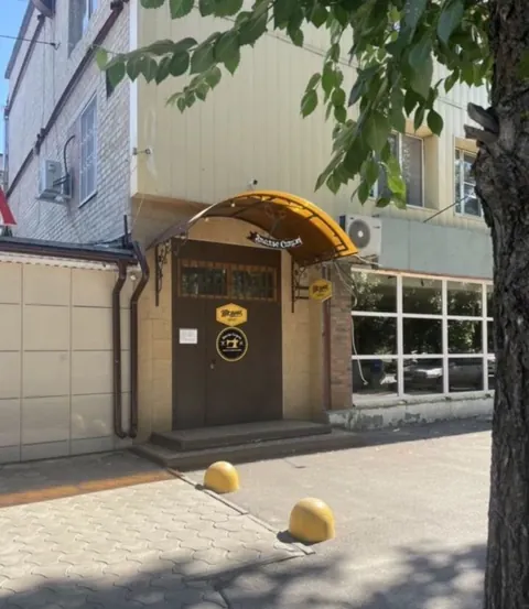 Вход с улицы: дверь под жёлтым козырьком с круглым знаком ателье Силуэт
